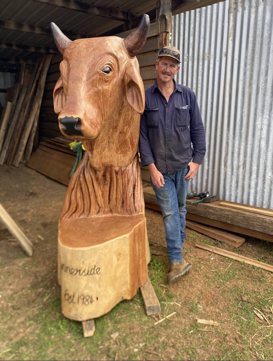 Will from Cossy's Chainsaw Artistry with a hand-carved bull sculpture