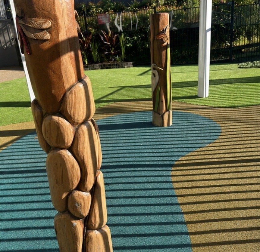 Carved timber nature play posts on coloured rubber softfall