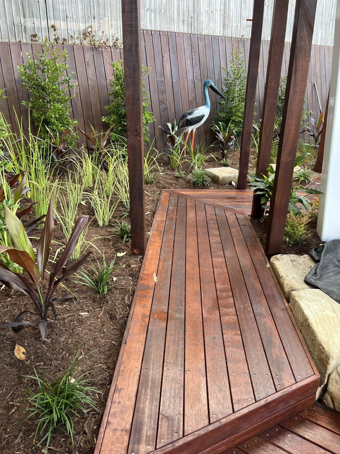 Timber boardwalk with bird sculpture and native garden beds