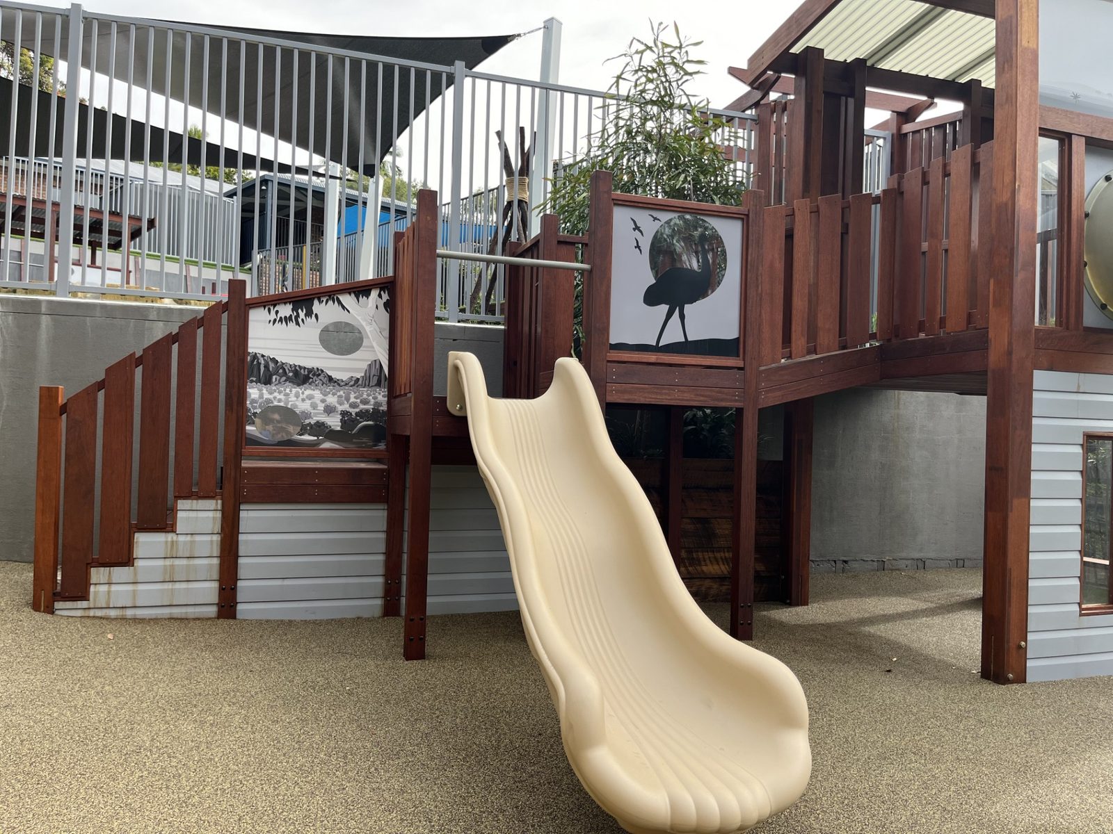 Custom timber play structure with slide and native animal artwork on rubber softfall