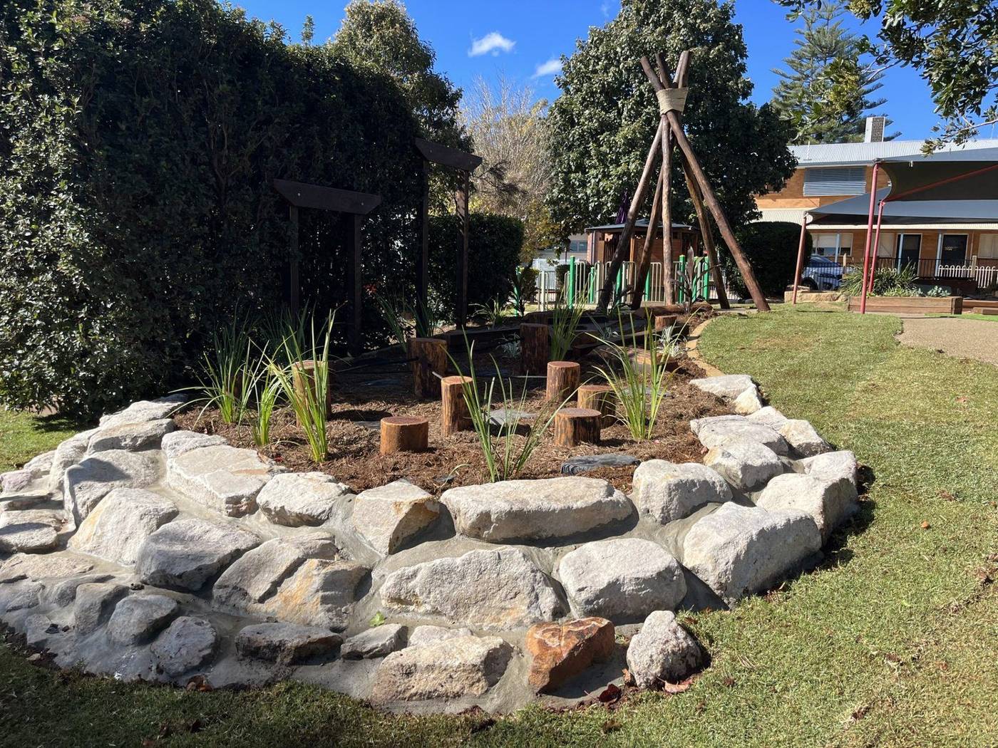 Yarning circle with sandstone boulders, log seating and native plantings