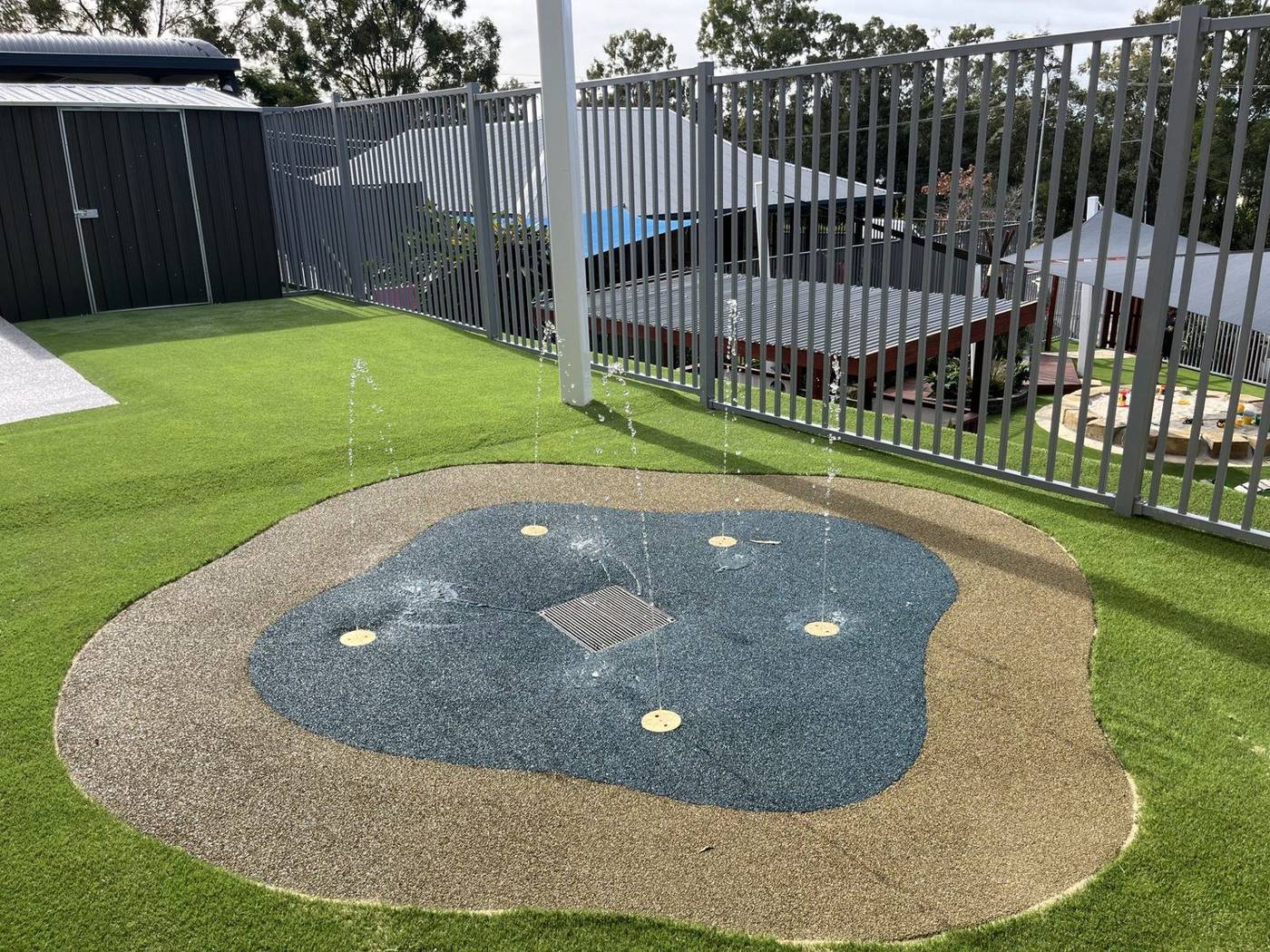 Splash pad with coloured rubber softfall and active water jets